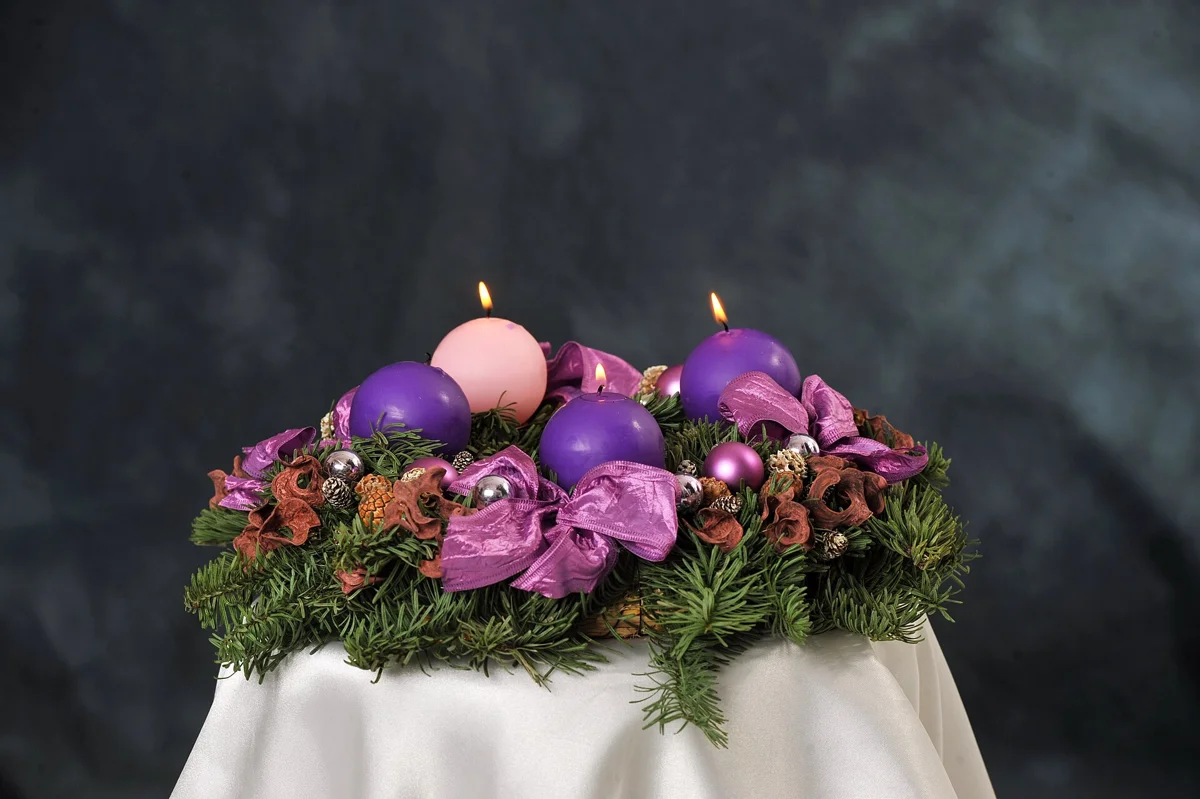 An Advent wreath with three lit candles, the countdown that sets the Budapest Christmas market dates
