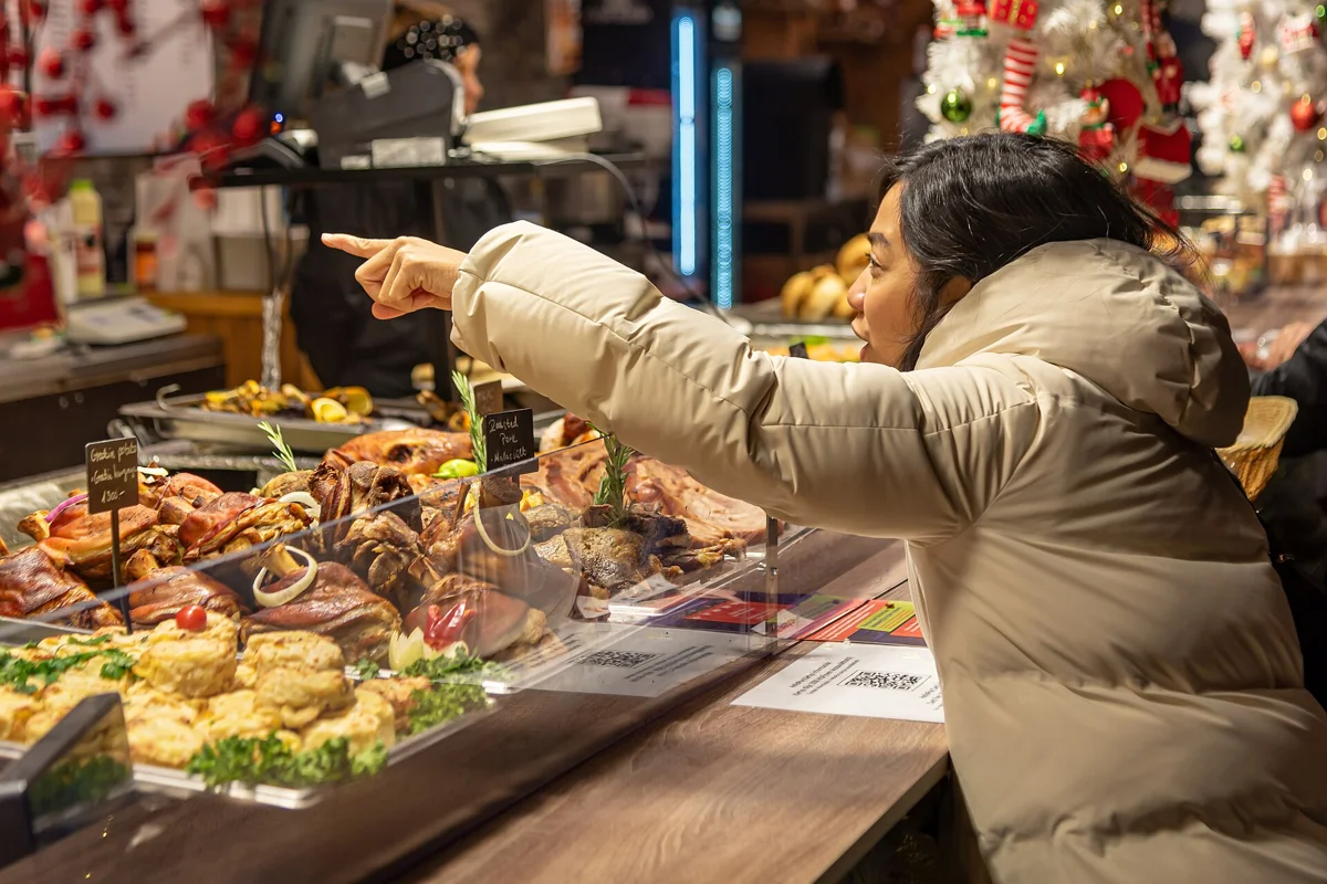 A traveller buying from a food stall at the Basilica market on a Budapest Christmas market walking tour