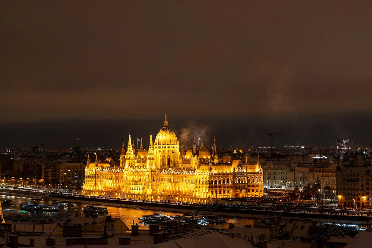 The floodlit Parliament across the Danube on a snowy December night, seen on a Budapest Christmas market tour by the river