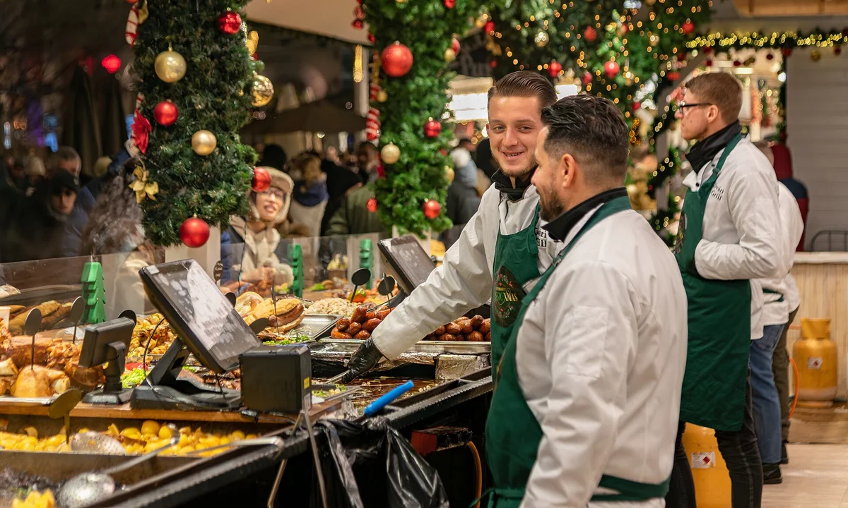Cooks serving at a Christmas market food stall where the Budapest chimney cake is sold